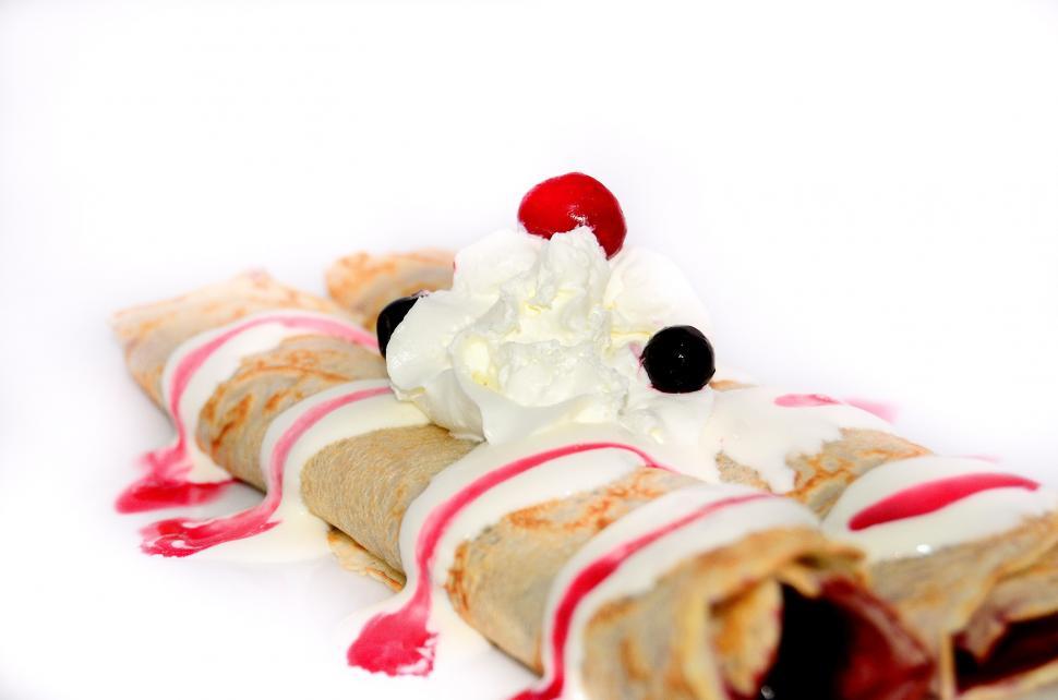 Free Image of Rolled Up Pastry With Whipped Cream and Cherry On Top 
