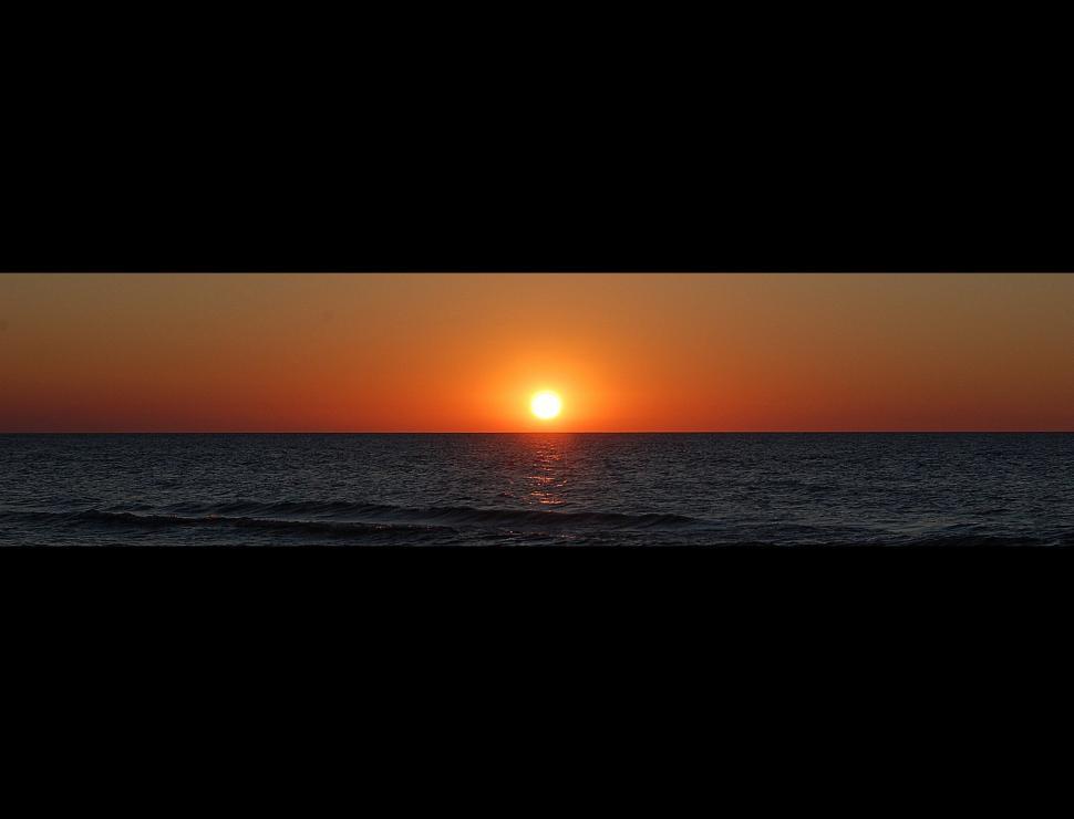 Free Image of The Sun Sets Over the Ocean on a Clear Day 