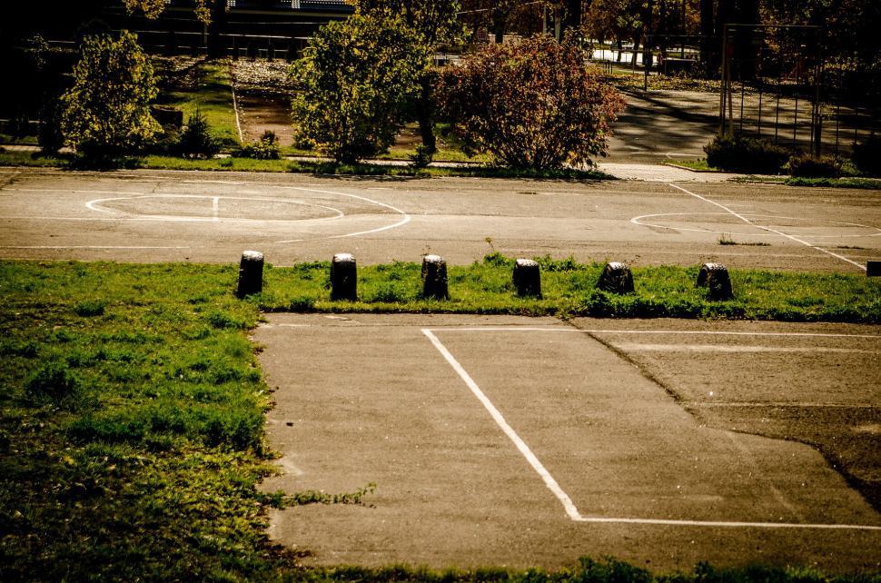 Free Image of Empty Basketball Court Surrounded by Grass and Trees 