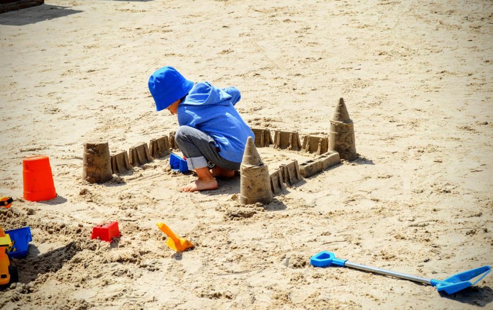 Free Image of A child plays with sand, sculpting a sand castle on a sandy beach. Baltic Sea  