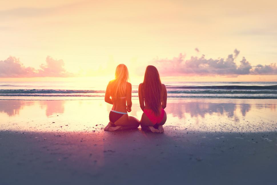 Free Image of Two Young Women Watching the Sunset Over the Ocean 