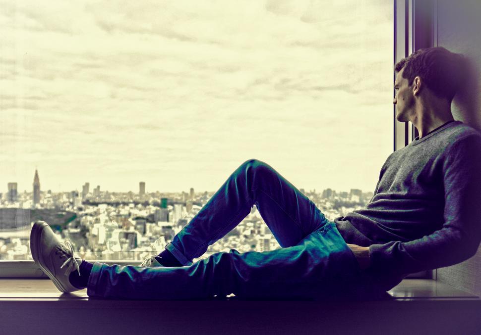 Free Image of Young Man Enjoying the City View at the Window - With Copyspace 