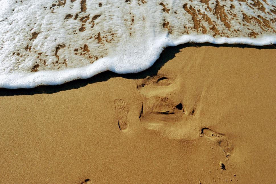 Free Image of The imprint of a bare foot on the sand near the sea with a running wave 