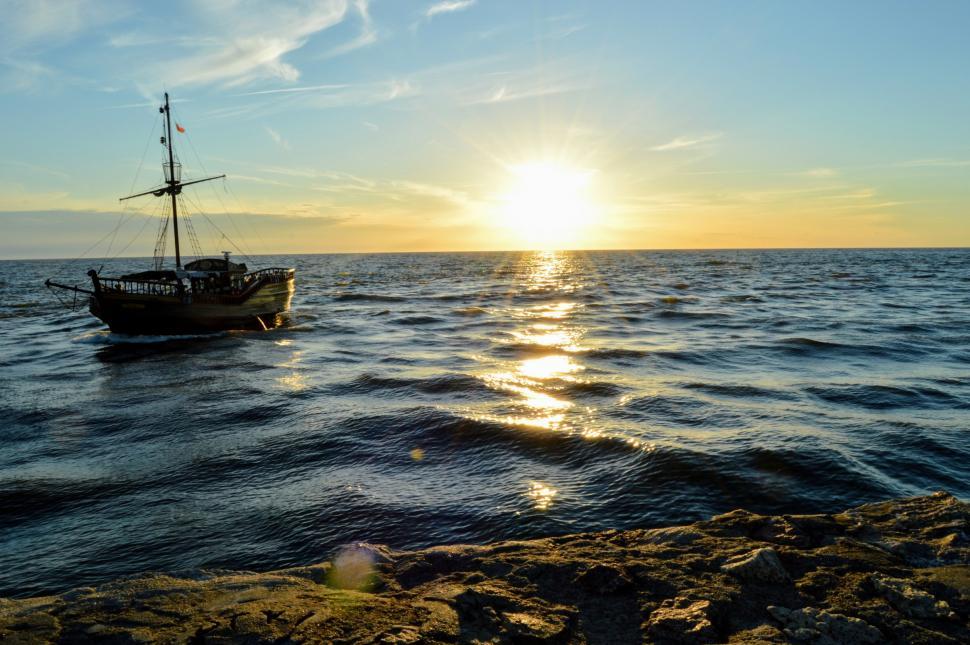 Free Image of Sailing ship floating in the sea against the backdrop of the setting sun 