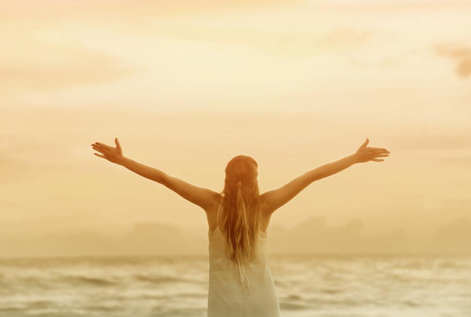 Free Image of Woman with Raised Arms at Sunset on the Beach 
