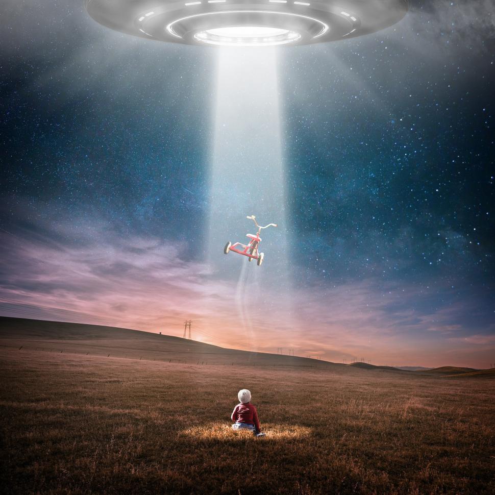 Free Image of Man Sitting in Field Under Flying Object 