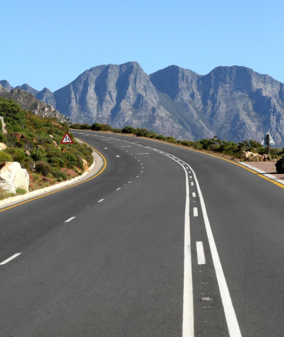 Free Image of Curved Road With Mountains in the Background 