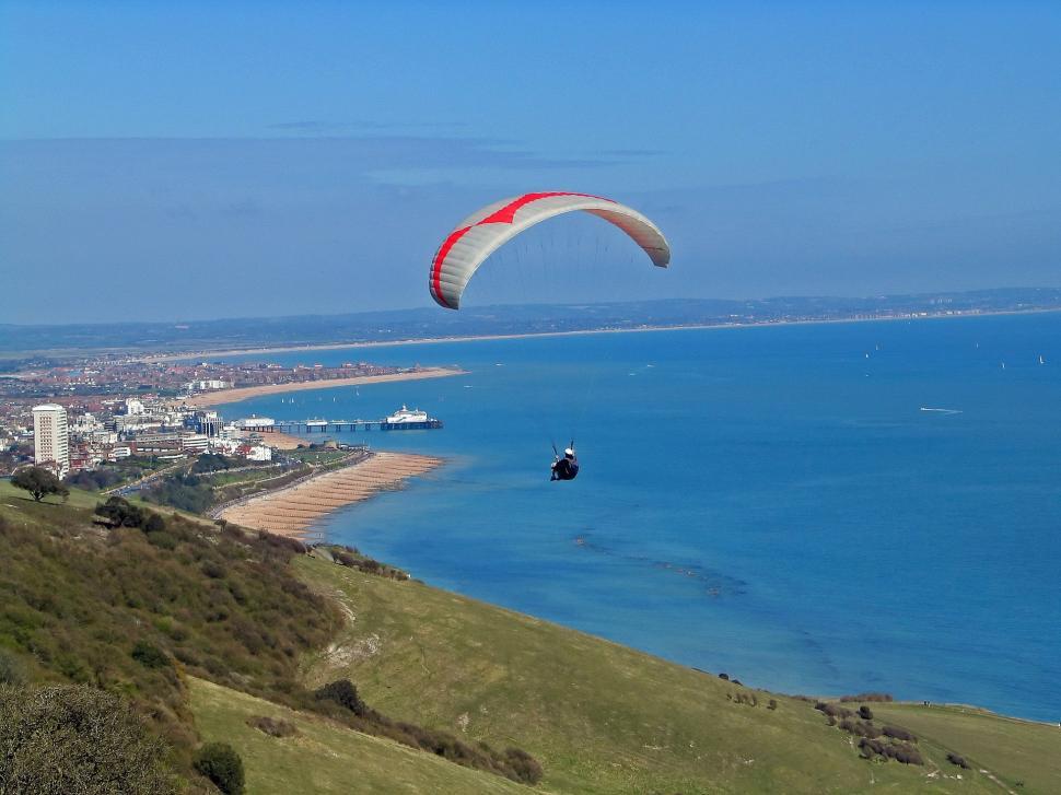 Free Image of Paraglider Soaring Over Ocean With City Background 