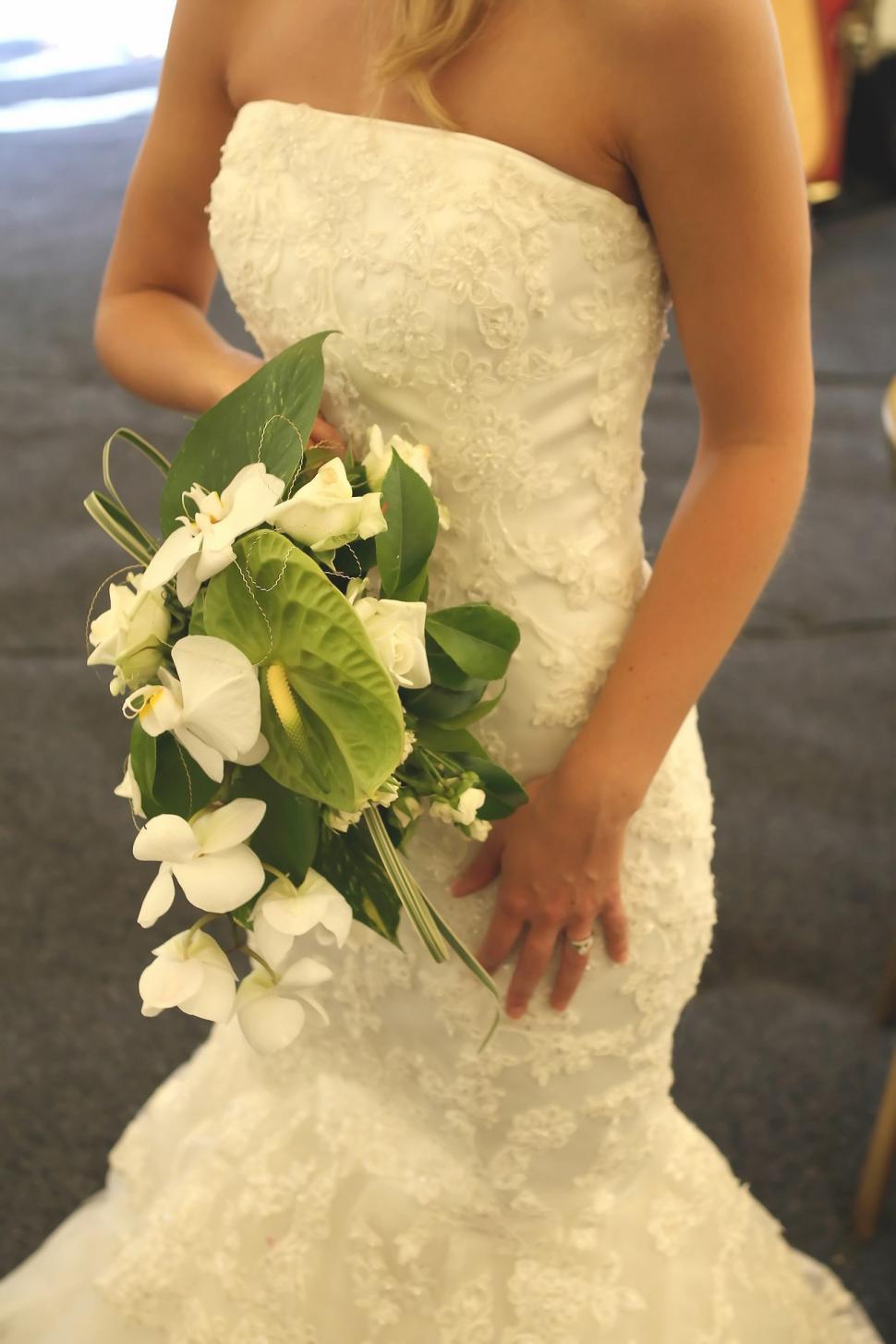 Free Image of Woman in Wedding Dress Holding Bouquet of Flowers 