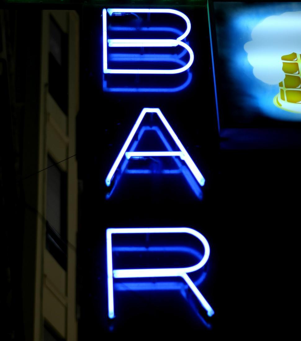Free Image of Neon Sign for Bar With TV in Background 