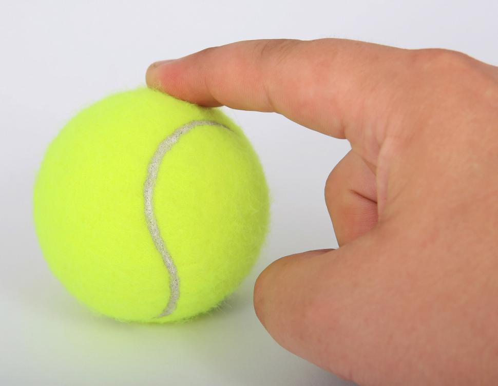 Free Image of Hand Holding Tennis Ball on White Surface 