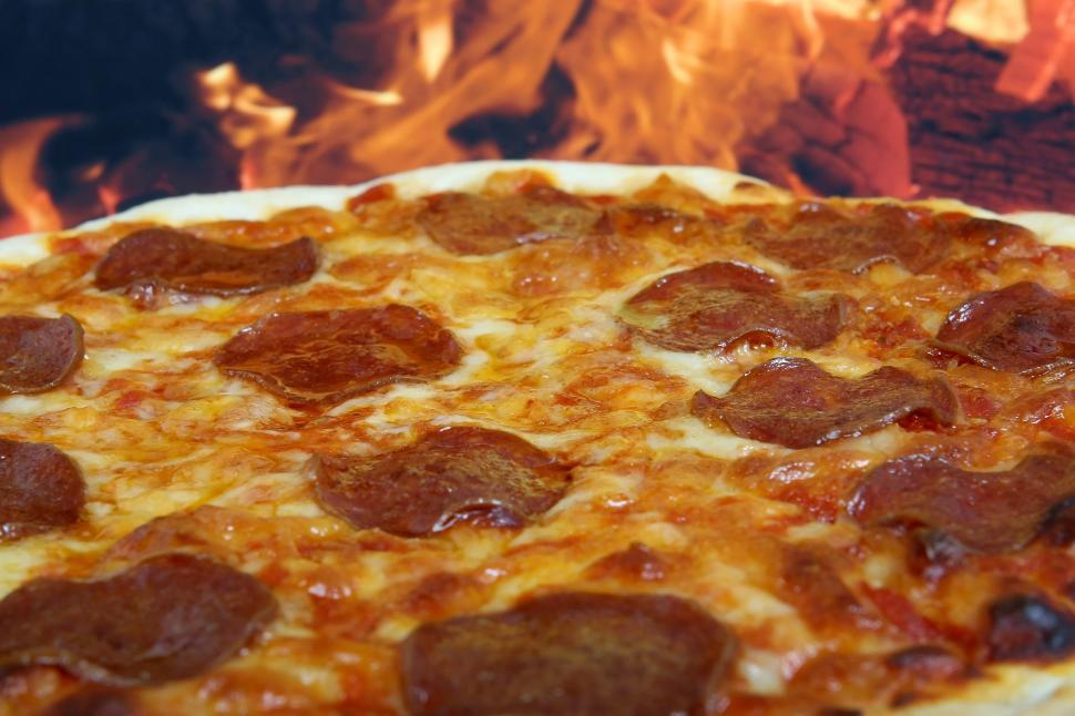Free Image of Pizza on Pizza Pan in Front of Fire 