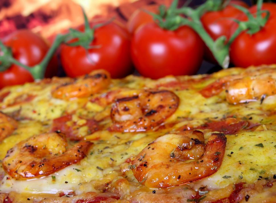 Free Image of Close Up of Pizza With Tomatoes in Background 