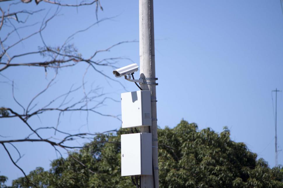 Free Image of Security camera with trees in the background 