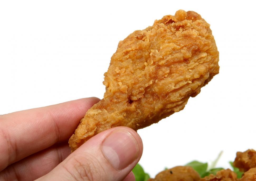 Free Image of Hand Holding Fried Chicken Nugget Over Pile of Lettuce 