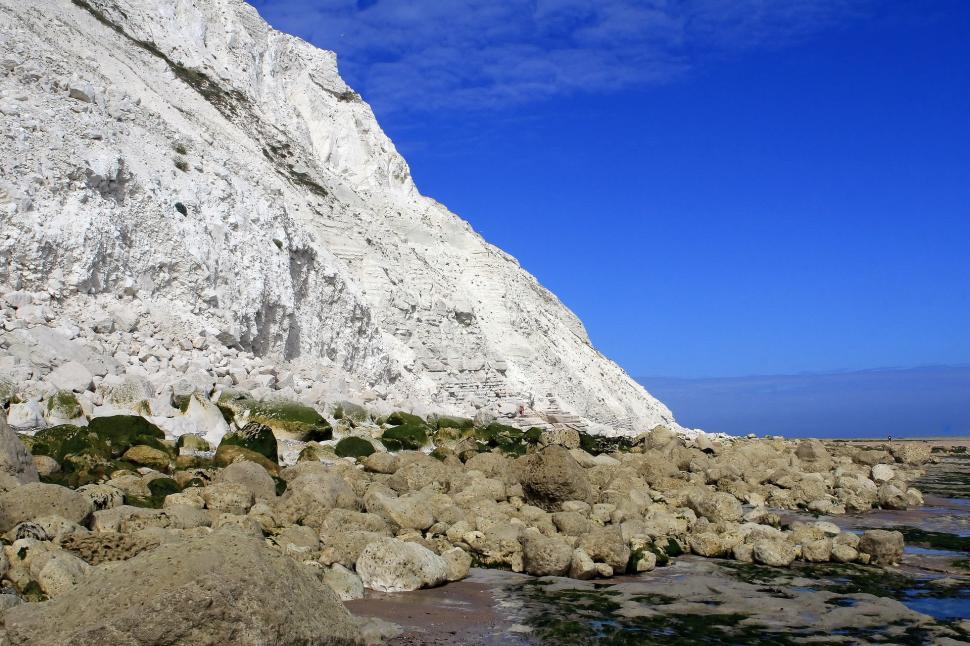 Free Image of Rocky Beach With Large White Mountain in Background 