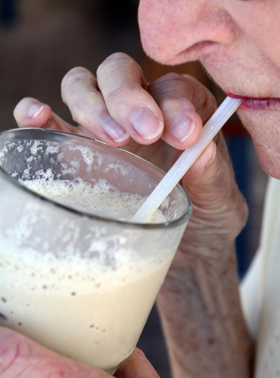 Free Image of Older Woman Drinking a Glass of Milkshake 