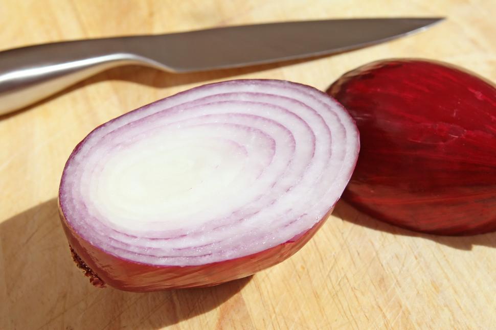 Free Image of A Red Onion and a Knife on a Cutting Board 
