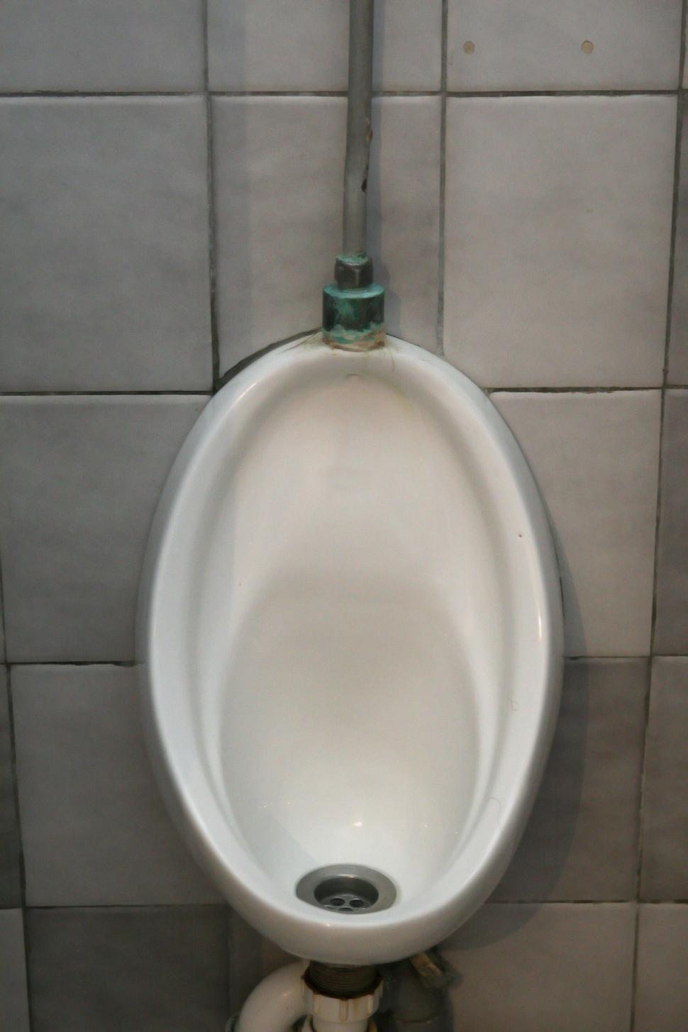 Free Image of White Urinal Mounted to Wall in Bathroom 