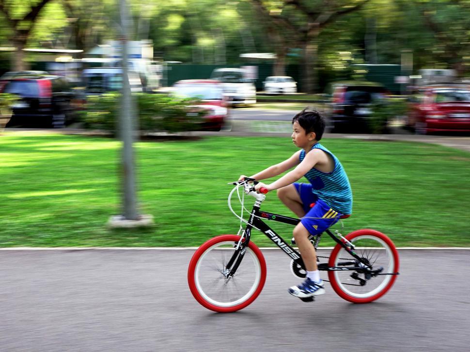 Free Image of Young Boy Riding Bike Down Street 