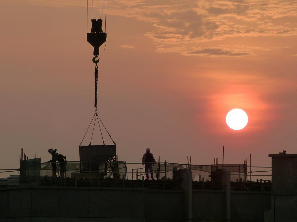 Free Image of Sun Setting Behind Crane on Building 