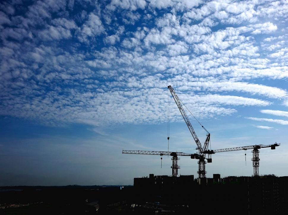 Free Image of Crane Silhouetted Against Blue Sky With Clouds 
