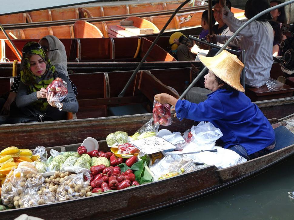 Free Image of Woman Sitting in Boat Filled With Fruits and Vegetables 