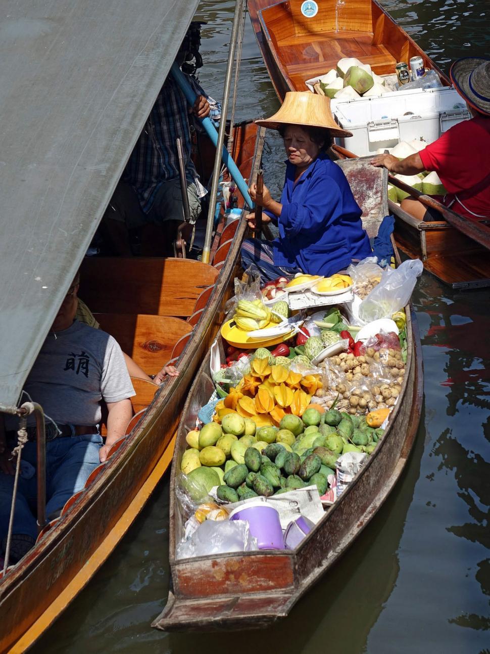 Free Image of Woman Sitting in Boat Filled With Fruits and Vegetables 