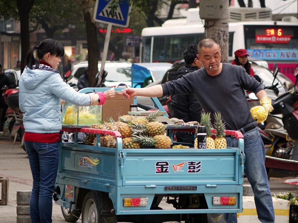 Free Image of Man Pushing Cart Full of Pineapples 