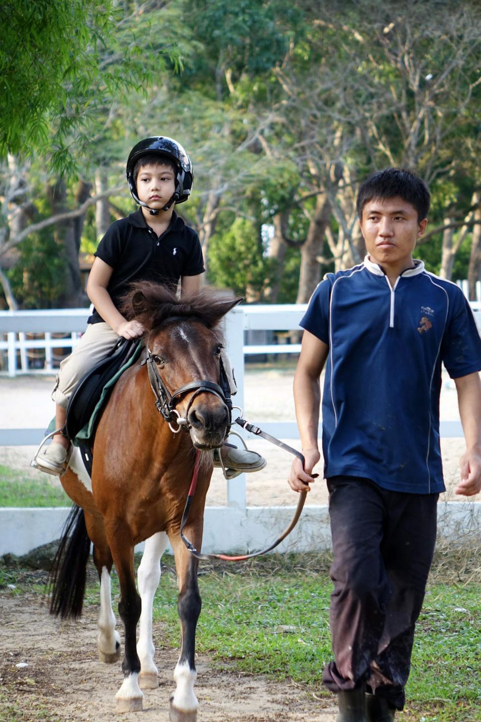 Free Image of Young Boy Riding on Brown and White Horse 