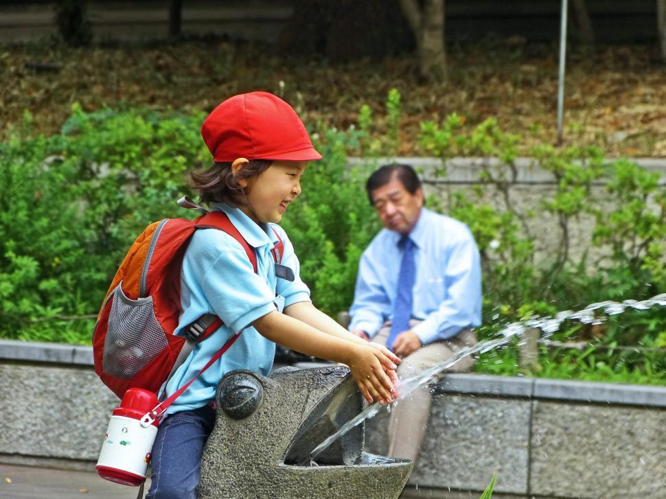 Free Image of Man and Little Girl Playing With Water Fountain 