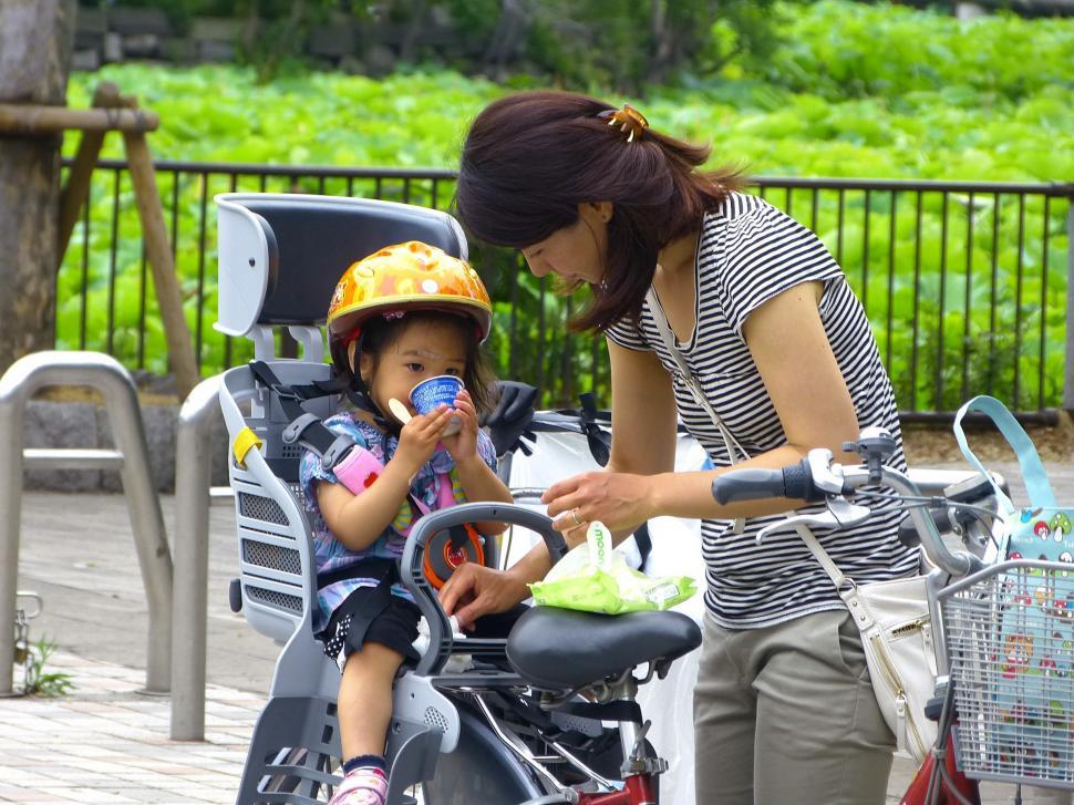 Free Image of Woman Feeding Child on Scooter 