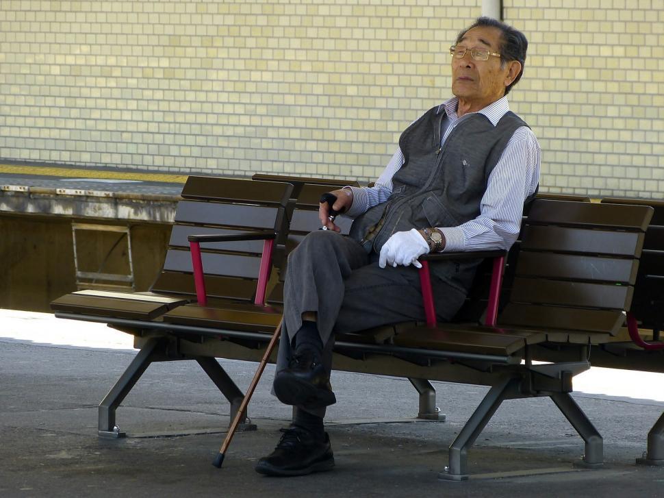 Free Image of Man Sitting on Bench With Cane 