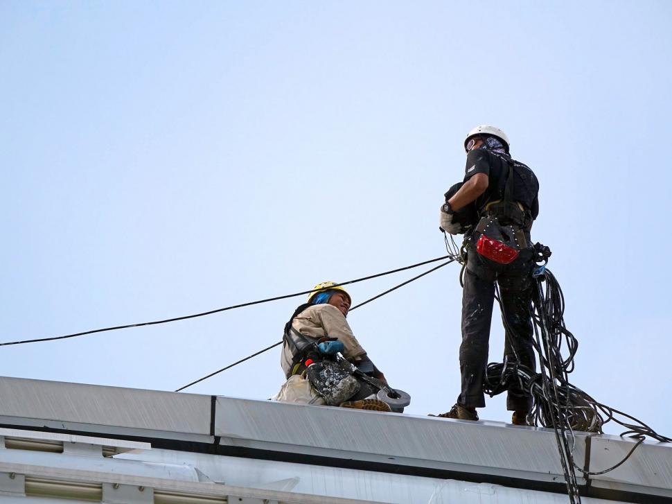 Free Image of Two Men on Top of a Building With Ropes 