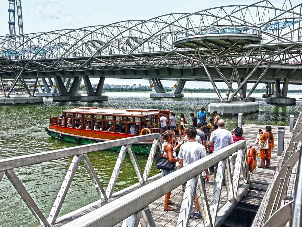 Free Image of Group of People Walking Across Bridge Over Water 