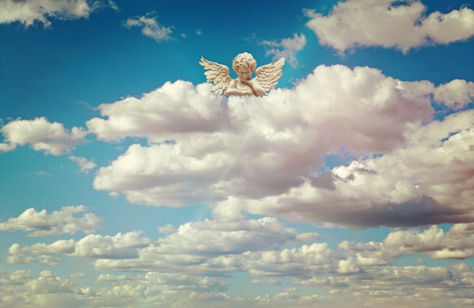 Free Image of White Angel Sitting on Top of a Cloud in the Sky 