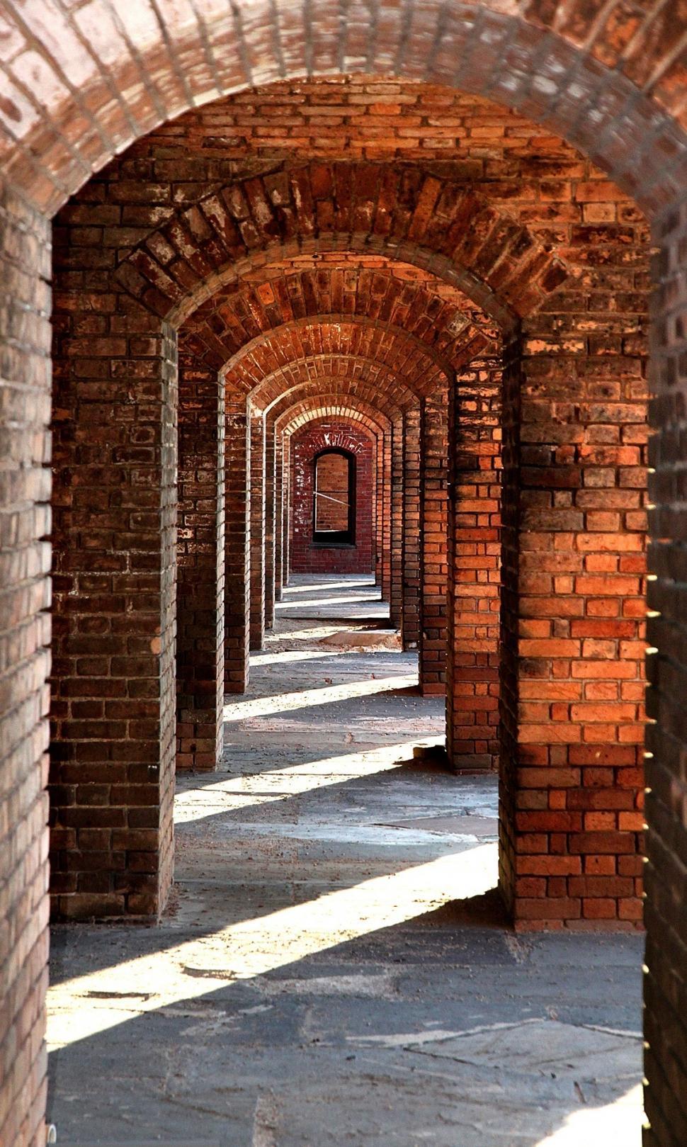 Free Image of Long Brick Tunnel With Clock on Wall 
