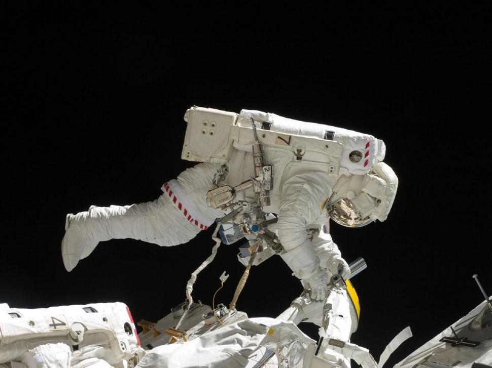 Free Image of Man in White Space Suit Standing on Pile of Debris 