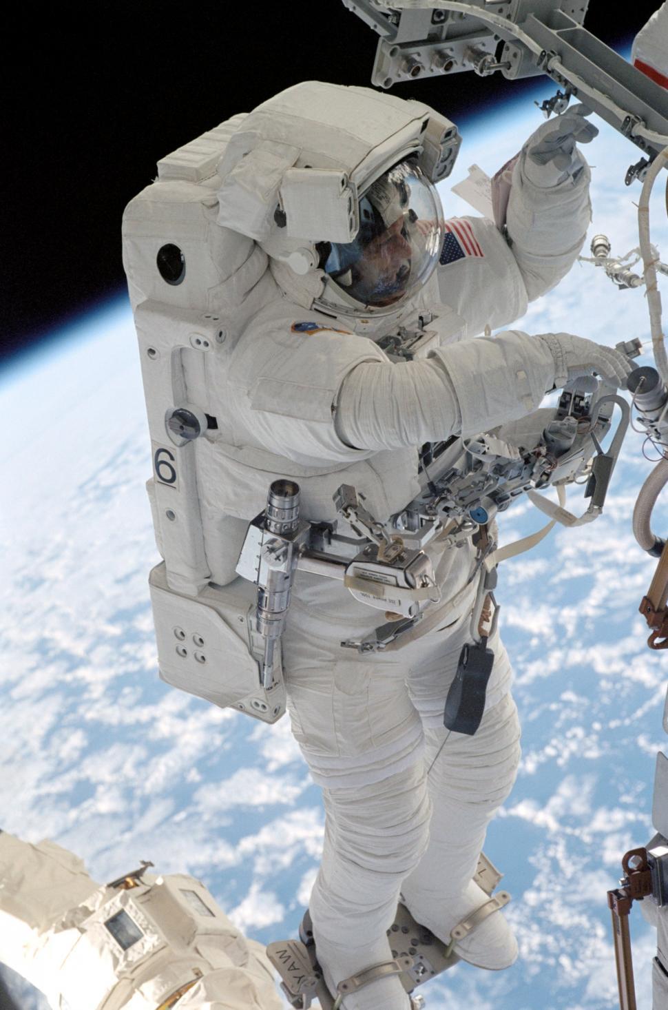 Free Image of Astronaut in White Space Suit Standing in Front of Earth 