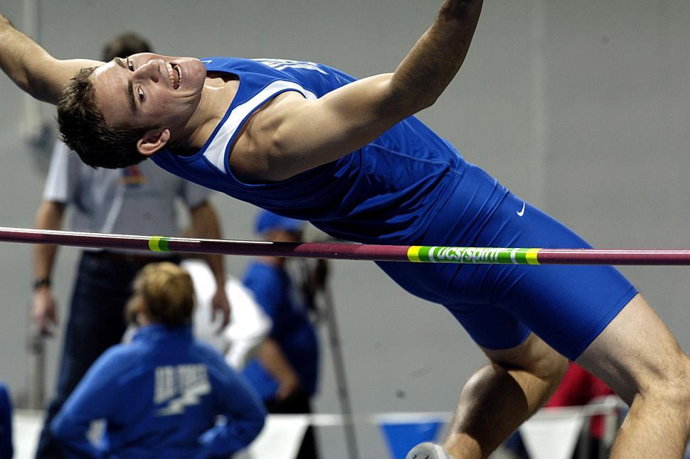 Free Image of Man Jumping Over High Bar in Blue Shirt and Shorts 