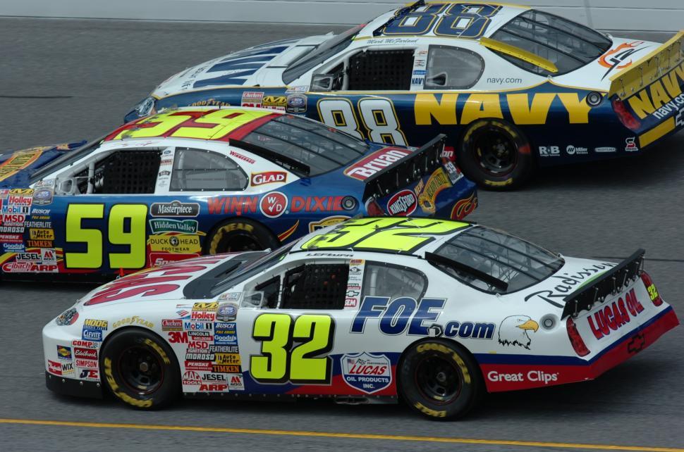 Free Image of Three NASCAR Cars Racing on a Track 
