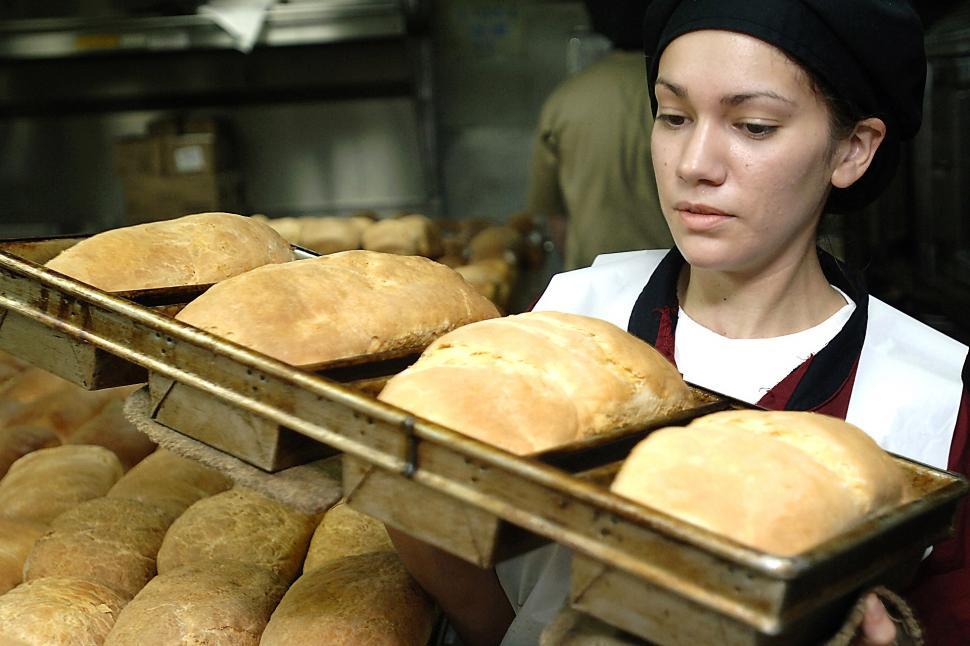 Free Image of Woman Holding a Tray of Loaves of Bread 