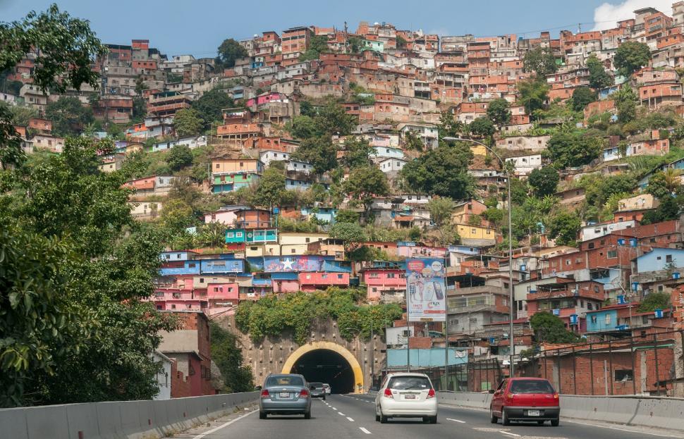 Free Image of Cars Driving Down a Road in Front of a Hillside 