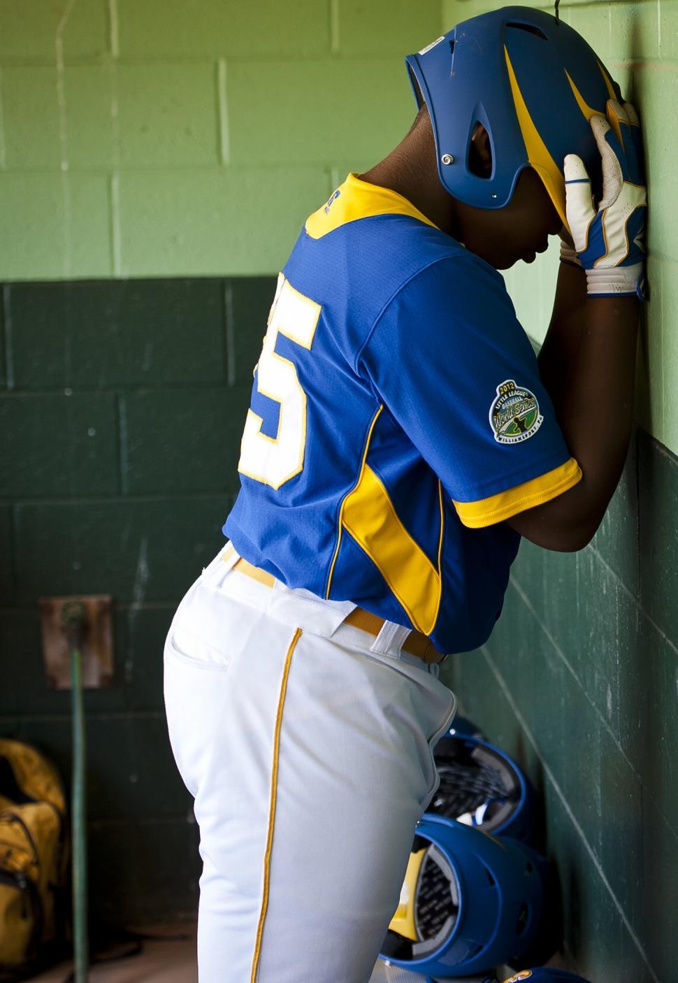 Free Image of Baseball Player Leaning Against Wall in Dugout 
