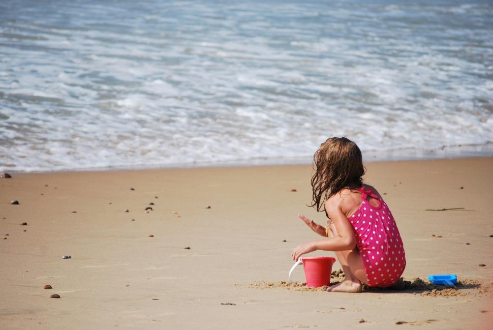 Free Image of Little Girl Sitting on Top of a Sandy Beach 