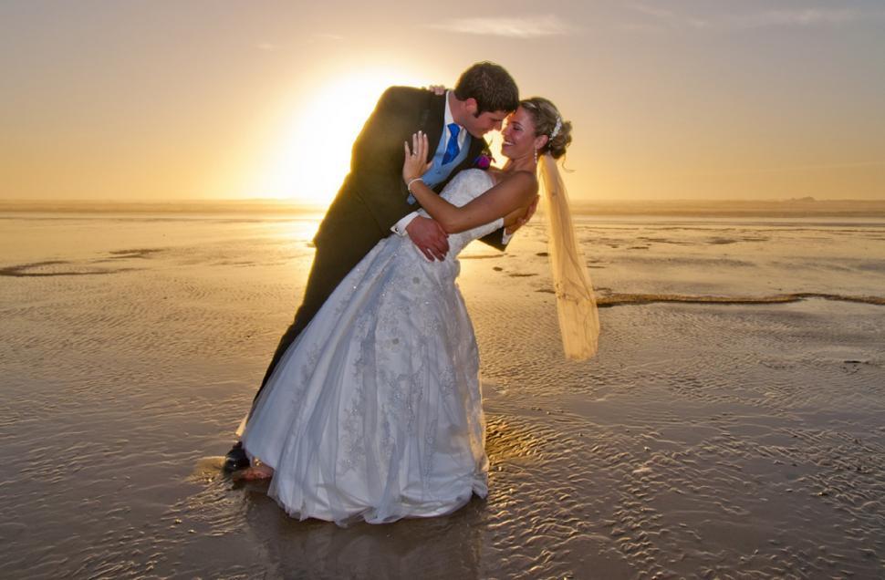 Free Image of Bride and Groom Kissing on Beach at Sunset 