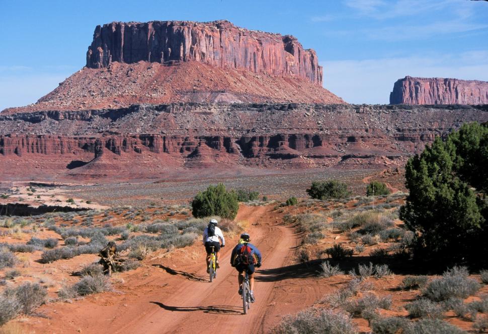 Free Image of Couple Riding Bikes Down Dirt Road 