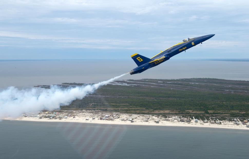 Free Image of Blue and Yellow Jet Flying Over a Body of Water 