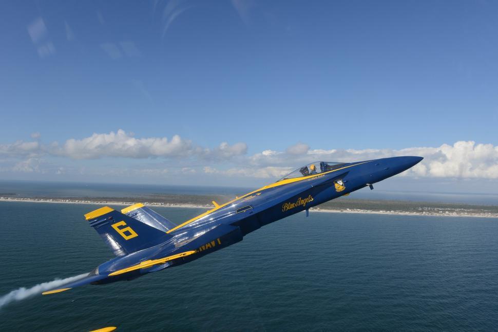 Free Image of Blue and Yellow Fighter Jet Flying Over the Ocean 