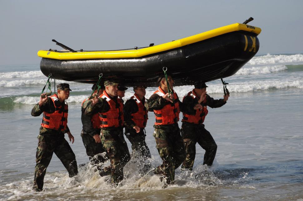 Free Image of Men Carrying Raft Across Body of Water 